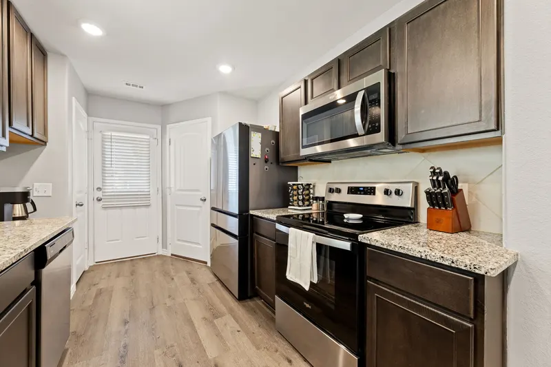 Kitchen with dark wood cabinets, granite counters and stainless appliances